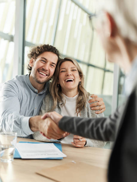 Young happy couple came to a successful agreement with their real estate agent during a meeting in the office.